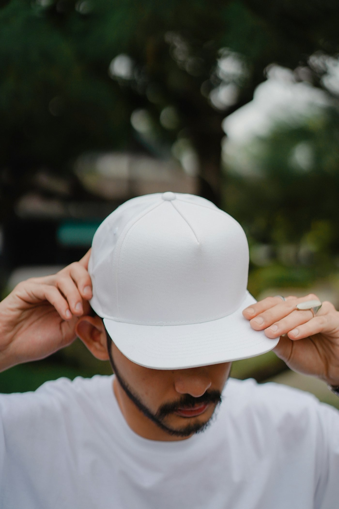 Chico acomodándose una gorra blanca de visera plana